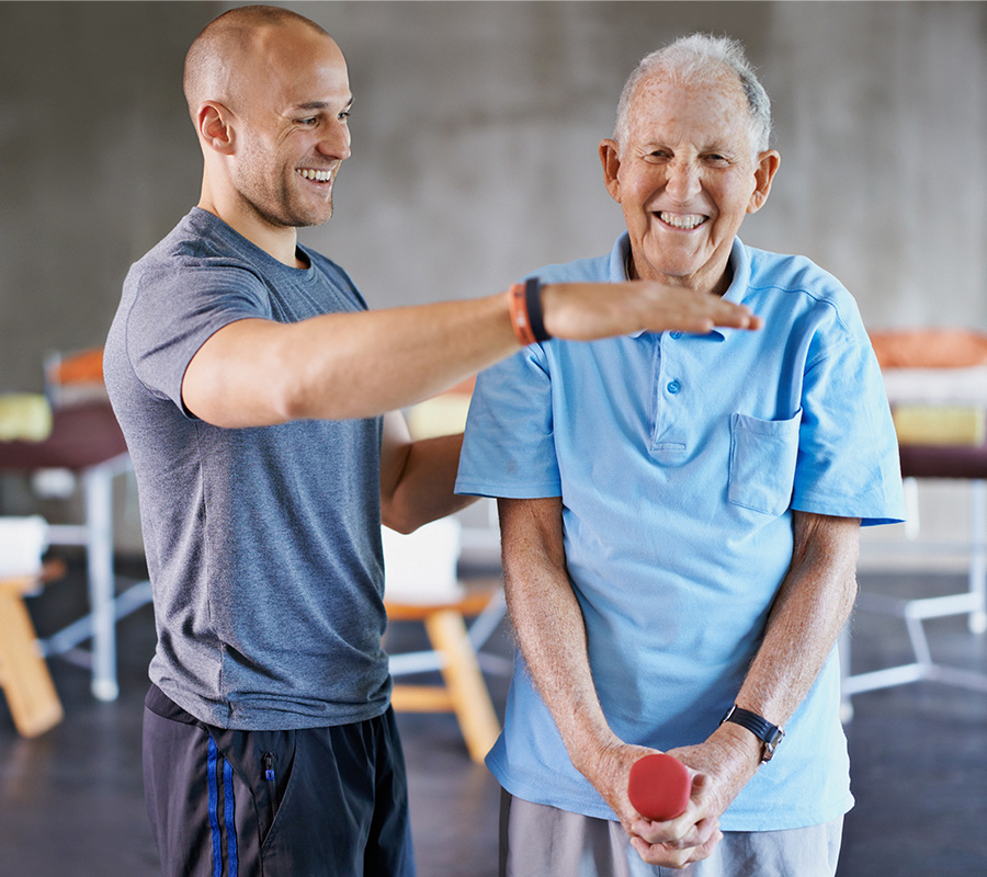 Male physiotherapist helping patient in performing exercise with dumbbell