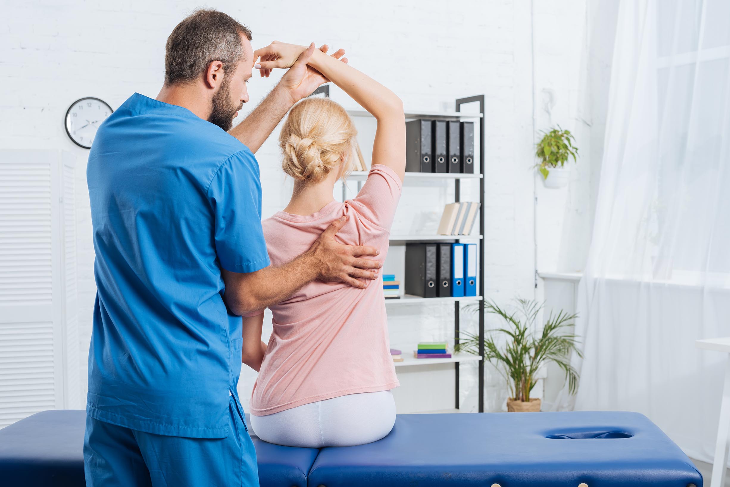 physiotherapist stretching patients arm on massage table in hosp
